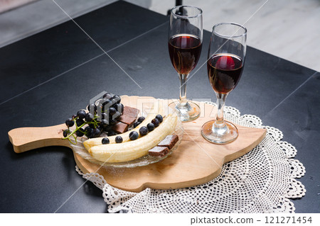 Romantic setup with wine, fruit, and dessert on a wooden board. Romantic setup with wine, fruit, and dessert on a wooden board. 121271454
