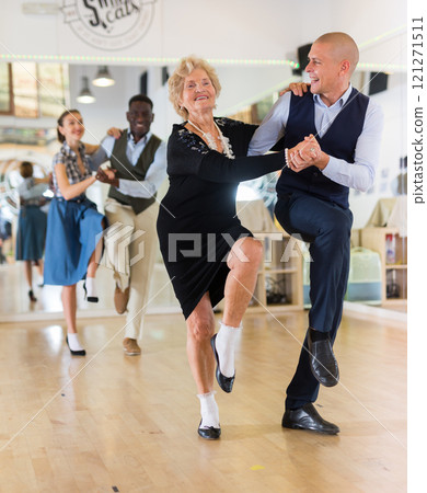 Senior woman and younger man dancing swing in studio 121271511