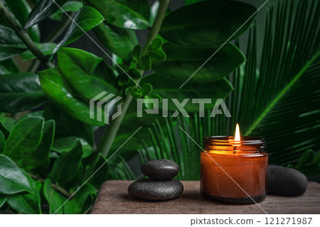 Burning massage candle with zen stones and green plants 121271987