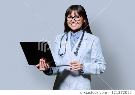 Portrait of female doctor with laptop on gray background 121272033