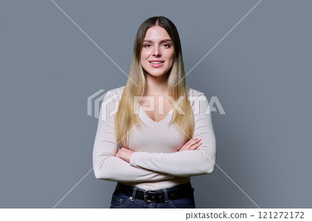 Portrait of young confident woman with crossed arms on grey background 121272172