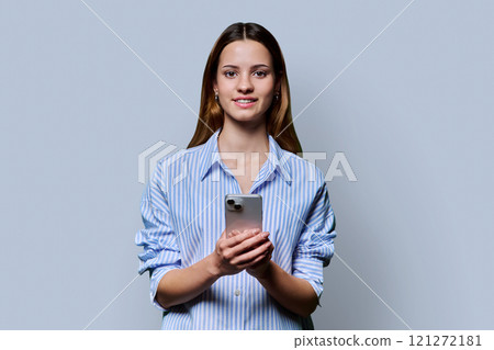 Young beautiful woman using smartphone on grey studio background 121272181
