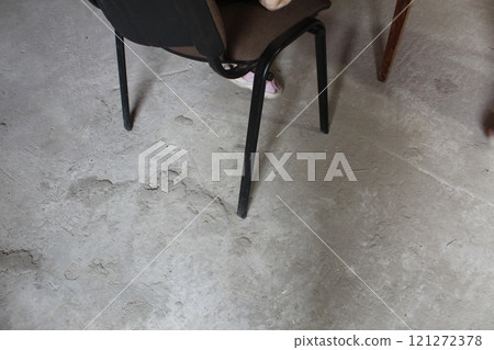 Chair legs on concrete. Life in an unfinished building, refugees Chair legs on concrete. Life in an unfinished building, refugees 121272378