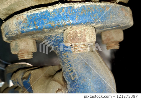 A nut screwed onto a rusty bolt connecting the flange of the blue steam valve A nut screwed onto a rusty bolt connecting the flange of the blue steam valve 121275387