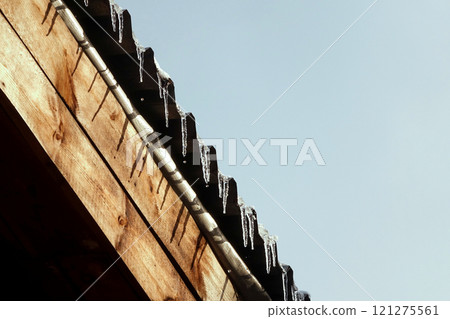First winter icicles dripping droplets with a wavy roof hemmed wooden planks First winter icicles dripping droplets with a wavy roof hemmed wooden planks 121275561