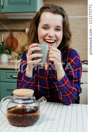 cheerful woman enjoying cup of coffee or tea. lovely lady is sitting at kitchen table and smiling cheerful woman enjoying cup of coffee or tea. lovely lady is sitting at kitchen table and smiling 121275771