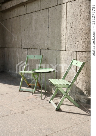 outdoor cafe, green table and chair on background of stone wall. tourist spot for breakfast, lunch. outdoor cafe, green table and chair on background of stone wall. tourist spot for breakfast, lunch. 121275785