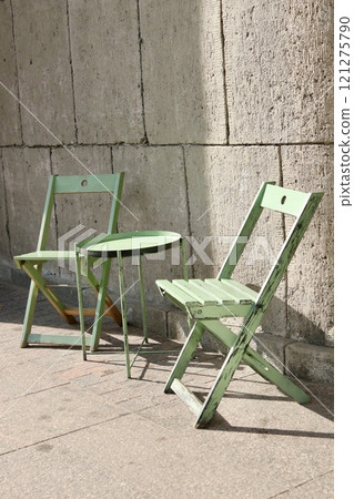 outdoor cafe, green table and chair on background of stone wall. tourist spot for breakfast, lunch. outdoor cafe, green table and chair on background of stone wall. tourist spot for breakfast, lunch. 121275790