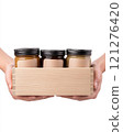 Farmers hands present a beautifully crafted wooden box containing jars of honey with organic labels. 121276420
