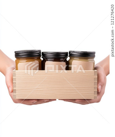 Farmers hands present a beautifully crafted wooden box containing jars of honey with organic labels. 121276420
