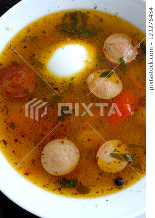 Hearty Spicy Vegetable Soup With Sausages and Egg Served in a Bowl 121276434