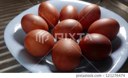 Plate holding painted red Easter eggs with textured eggshell placed on table 121276474