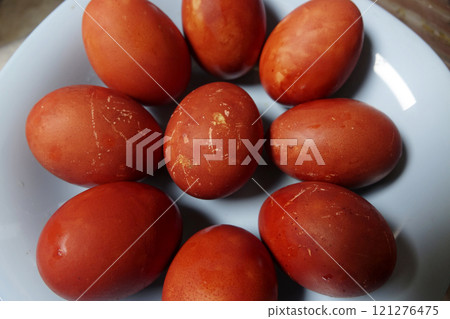 Plate is filled with numerous red Easter eggs with natural red-brown color and textured eggshells 121276475