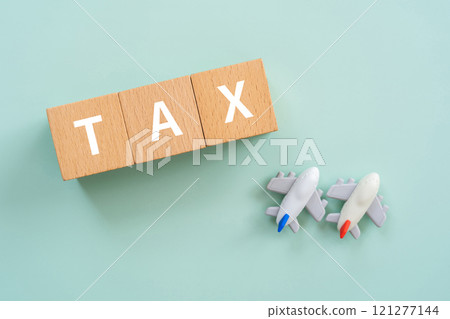 A block with the word TAX written on it, a calculator, and a model of an apartment building 121277144