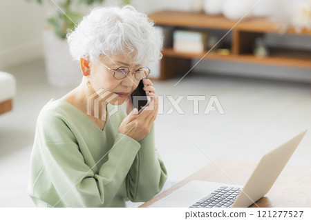 Senior woman making a phone call in the living room Senior woman making a phone call in the living room 121277527