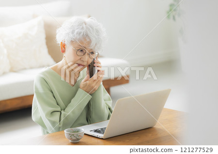Senior woman making a phone call in the living room Senior woman making a phone call in the living room 121277529