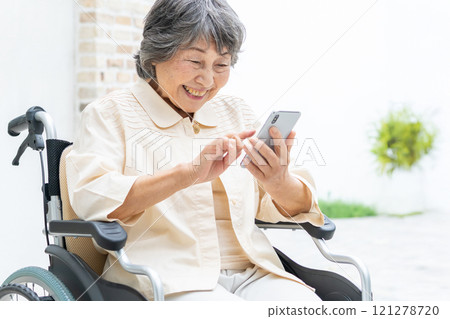 坐在輪椅上操作智慧型手機的高級女性 121278720