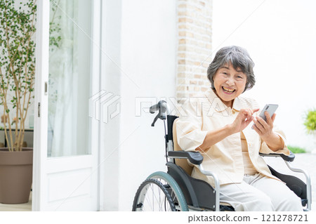 Senior woman in a wheelchair operating a smartphone Senior woman in a wheelchair operating a smartphone 121278721