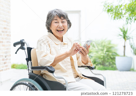 坐在輪椅上操作智慧型手機的高級女性 121278723
