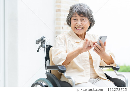 Senior woman in a wheelchair operating a smartphone 121278725