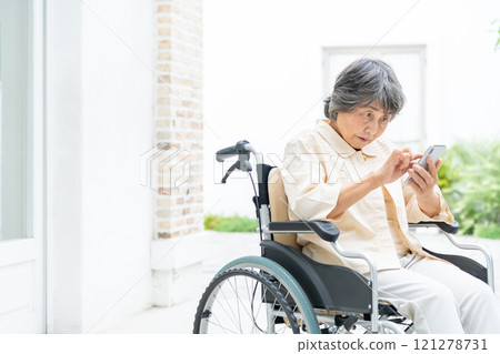 Senior woman in a wheelchair operating a smartphone Senior woman in a wheelchair operating a smartphone 121278731