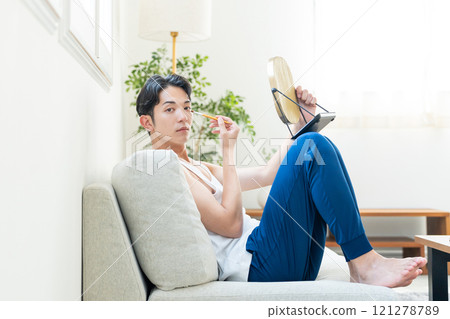 Young man putting on make-up in the living room Young man putting on make-up in the living room 121278789