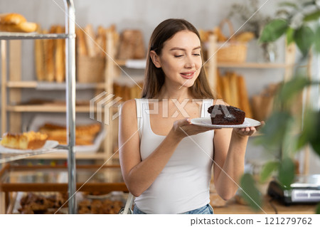 Satisfied female customer holding sweet pie in bakery interior Satisfied female customer holding sweet pie in bakery interior 121279762