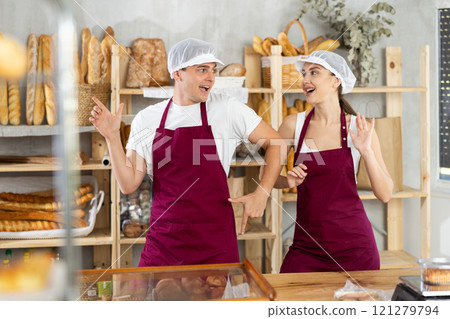 Woman and man sellers dance at counter in bakery Woman and man sellers dance at counter in bakery 121279794