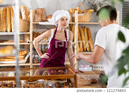 Young woman seller helps man buyer choose pastries Young woman seller helps man buyer choose pastries 121279803