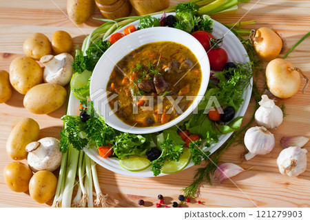 Tasty goulash from chicken hearts with lettuce at plate, fresh vegetables 121279903