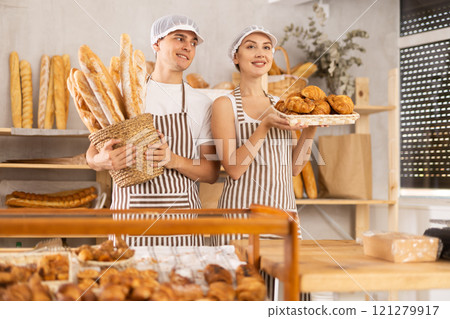 Young woman and guy sellers with baguettes and croissants in bakery 121279917