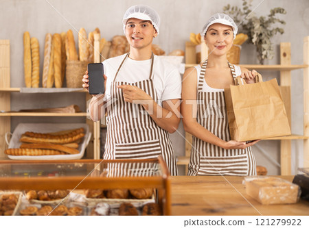 Young woman and guy sellers with bag and smartphone in bakery 121279922