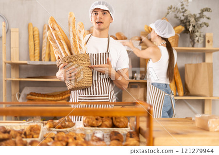 Young male seller with basket of baguettes 121279944