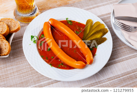 Two Viennese sausages with saftgoulash served on plate 121279955