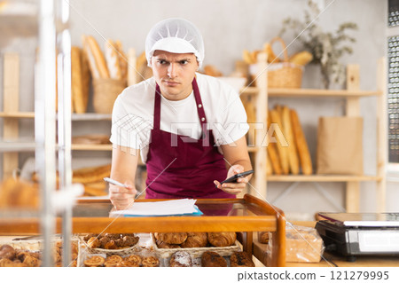 Worried bakery owner reviewing problematic order details using phone 121279995