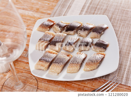 On table is plate with appetizer - pieces of salted Atlantic herring fillet On table is plate with appetizer - pieces of salted Atlantic herring fillet 121280020
