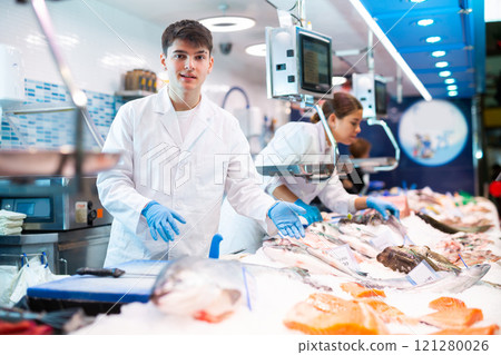 Positive shop assistants in work clothes posing in fish store Positive shop assistants in work clothes posing in fish store 121280026