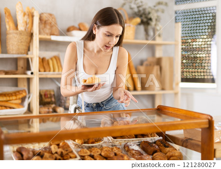 Young female buyer choosing croissants in bakery 121280027