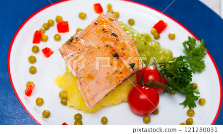 Tasty fried trout fillet with mashed potatoes, guacamole, tomatoes and greens 121280031