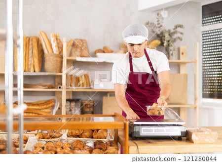 Skilled young baker weighing freshly baked pastries 121280044