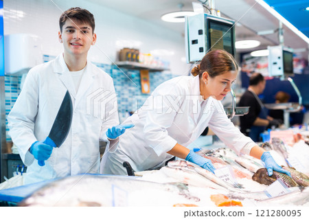 Positive shop assistants in work clothes posing in fish store Positive shop assistants in work clothes posing in fish store 121280095