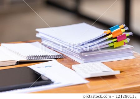 Paper documents are stacked on wooden desks at the workplace. 121280115