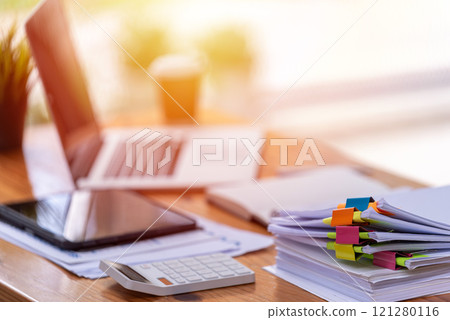 Paper documents are stacked on wooden desks at the workplace. 121280116