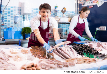 Positive salesman demonstrating calamary in fish store Positive salesman demonstrating calamary in fish store 121280232