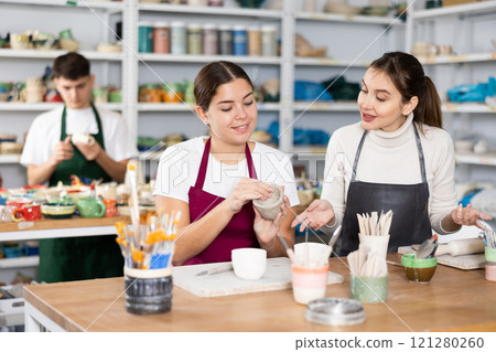 Two young women making pottery in workshop 121280260