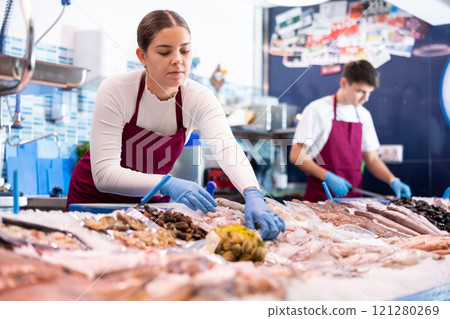 Positive saleswoman demonstrating calamary in fish store 121280269