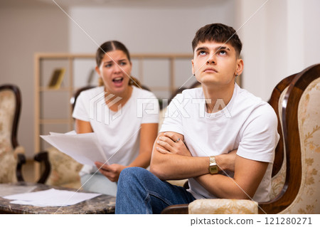 Portrait of upset man sitting while quarrel with wife at home Portrait of upset man sitting while quarrel with wife at home 121280271