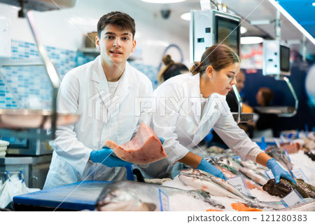 Male seller demonstrates large piece of tuna fillet at fish market Male seller demonstrates large piece of tuna fillet at fish market 121280383