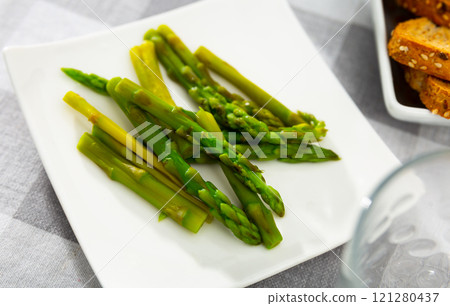 Fresh green asparagus with sunflower oil on white plate 121280437