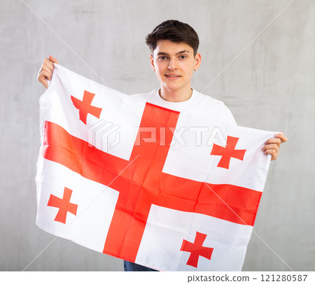 Smiling young guy holding flag of Georgia Smiling young guy holding flag of Georgia 121280587